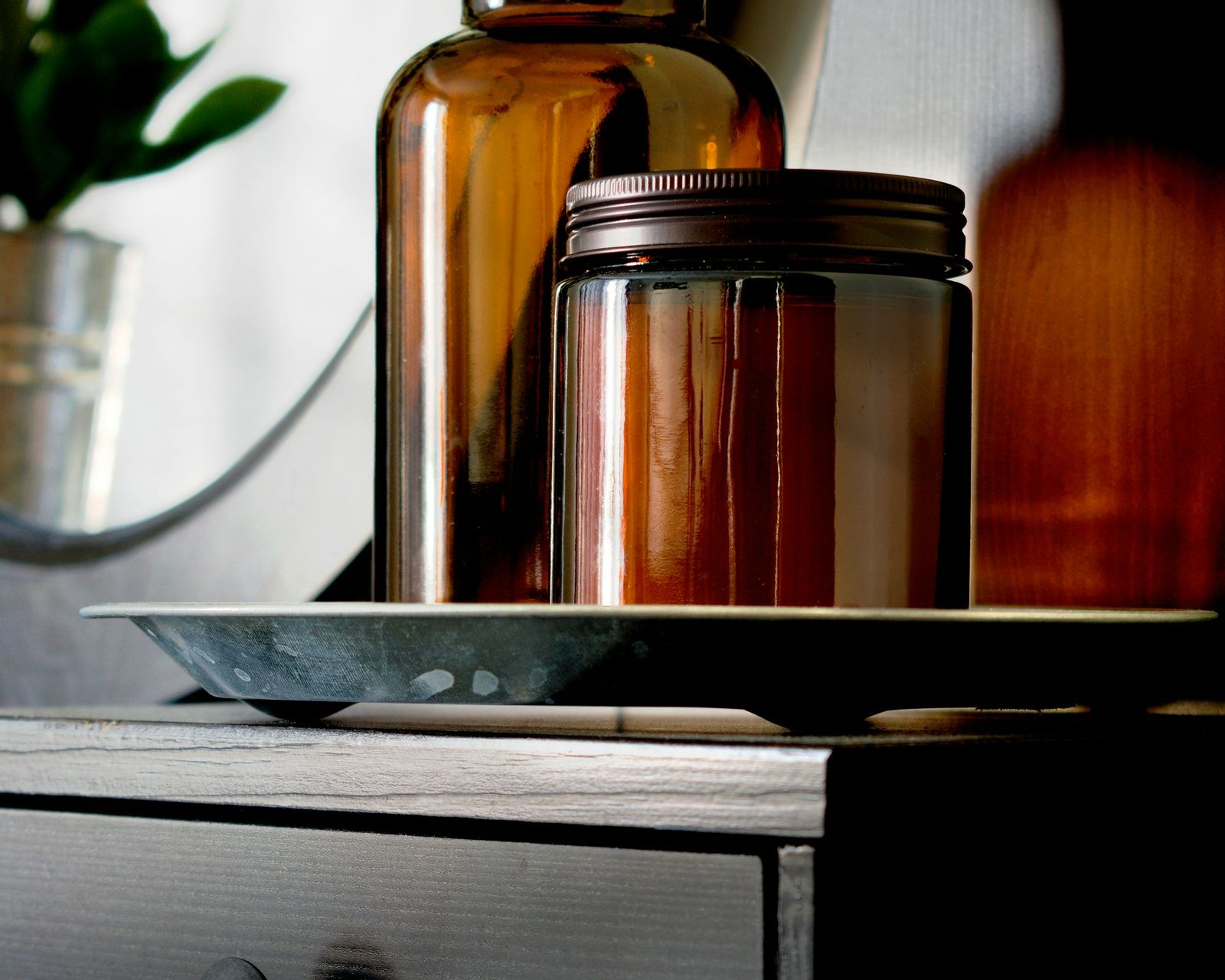 Unbranded amber-glass cosmetic jars styled on a warm neutral surface